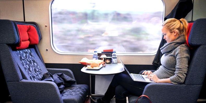 Kvindelig pendler i tog med computer i skødet